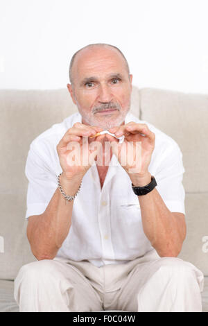 Älterer Mann bricht eine Zigarette als Symbolbild Quiting Rauchen Stockfoto