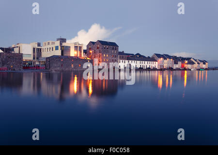 Gebäude am Ufer des Flusses während der Flut in der Stadt in der Dämmerung. Claddach, Galway, Irland. Stockfoto