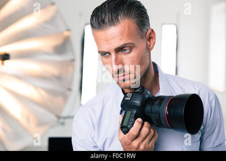 Porträt eines nachdenklich Fotografen Kamera halten und Blick in die Kamera im studio Stockfoto