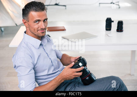Lächeln auf den Lippen schön Fotograf mit Kamera und Blick in die Kamera im studio Stockfoto
