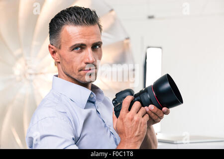 Porträt eines hübschen Fotografen Kamera halten und Blick in die Kamera Stockfoto