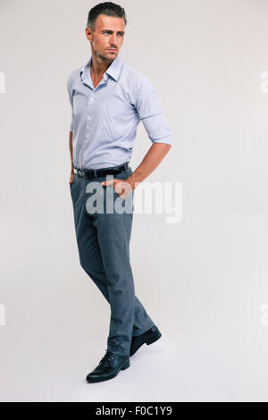 In voller Länge Portrait von ein nachdenklicher Mann steht auf grauem Hintergrund Stockfoto