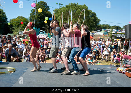 Familien beobachten einen akrobatischen Akt in der Sommersonne von Garküchen und Zelten am Hafen Eliot Festival Cornwall Stockfoto