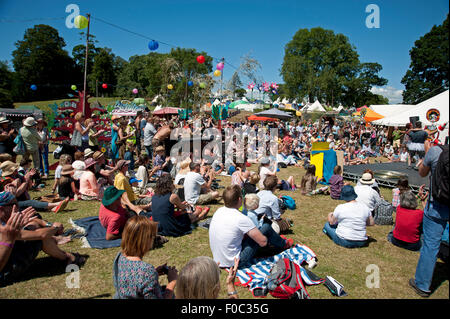 Familien beobachten einen akrobatischen Akt in der Sommersonne von Garküchen und Zelten am Hafen Eliot Festival Cornwall Stockfoto