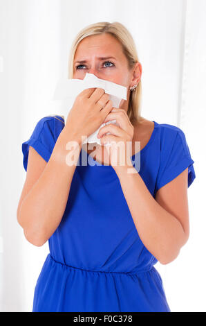 blonde Frau, die ihre Nase weht Stockfoto