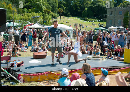 Familien beobachten einen akrobatischen Akt in der Sommersonne von Garküchen und Zelten am Hafen Eliot Festival Cornwall Stockfoto