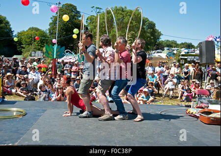 Familien beobachten einen akrobatischen Akt in der Sommersonne von Garküchen und Zelten am Hafen Eliot Festival Cornwall Stockfoto