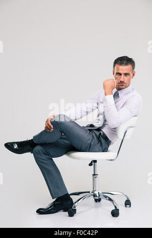 Porträt eines schönen Geschäftsmann sitzen auf Bürostuhl isoliert auf weißem Hintergrund Stockfoto