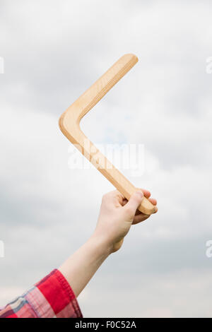 Niedrigen Winkel Ansicht von Hand mit Bumerang gegen bewölktem Himmel Stockfoto