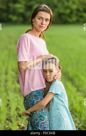 Porträt von Mädchen umarmt Mutter auf Feld Stockfoto