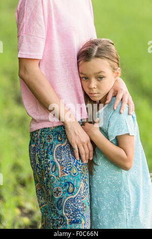 Trauriges Mädchen umarmt Mutter auf Feld Stockfoto