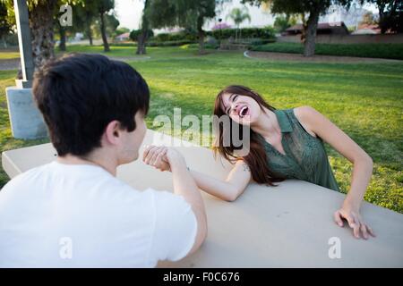 Junges Paar vorgibt, Ringen arm bei Picknickbank im Park Stockfoto