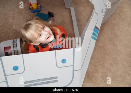 Junge Mädchen spielen in Karton Raumschiff mit Astronauten-Outfit, erhöht, Ansicht Stockfoto