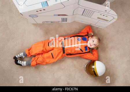 Junge Mädchen spielen, tragen Astronaut Outfit liegen neben Karton Raumschiff, erhöht, Ansicht Stockfoto