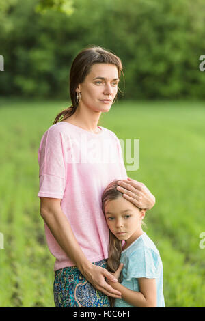 Mädchen umarmt Mutter auf Feld Stockfoto