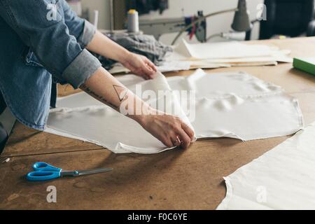 Junge weibliche Näherin Faltung Musterelement im Mode-studio Stockfoto