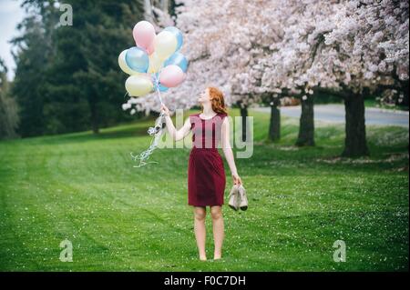 Junge Frau mit Haufen Luftballons im Frühlingspark Stockfoto