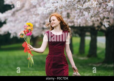 Junge Frau mit Blumen im Frühlingspark Stockfoto