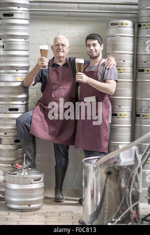 Zwei Brauereien trinken Bier in der Brauerei, neben Fässer Stockfoto