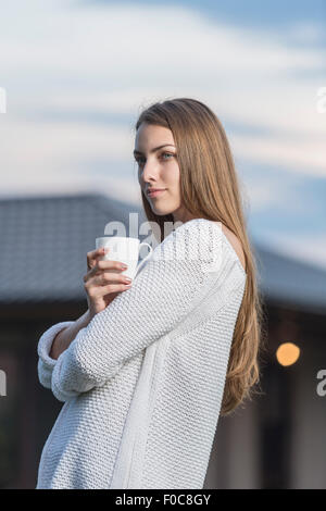 Schöne junge Frau, die Kaffeetasse im Freien halten Stockfoto