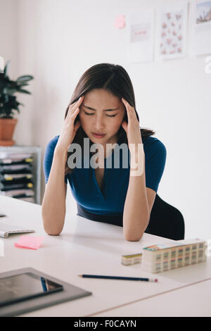 Junge Geschäftsfrau, leiden unter Kopfschmerzen am Schreibtisch Stockfoto