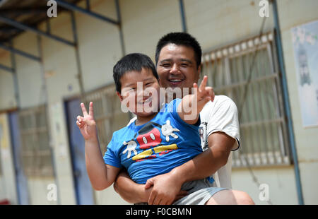 (150812)--NANNING, 12. August 2015 (Xinhua)--8-Year-Old Boy Xiao Nan, aus Osten Chinas Jiangxi Provinz, stellt mit seinem Vater auf einer Baustelle in Nanning, Hauptstadt von Süd-China Autonome Region Guangxi Zhuang, 12. August 2015. Fast tausend Bauarbeiter aus landesweit arbeiten auf der Baustelle der Lianqing Brücke in Nanning Stadt, weit weg von ihren Kindern und Haus. Manche Kinder können nicht warten, bis Frühlingsfest, das einzige Mal für die Eltern zu Hause, sondern nach Nanning Wiedersehen während ihrer Sommerferien kam. (Xinhua/Lu Boan) (Mt) Stockfoto