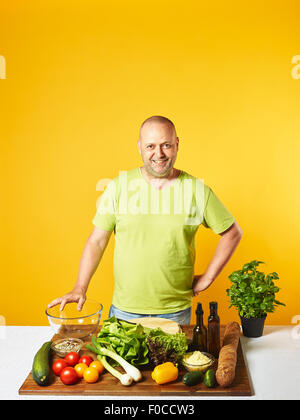 Frischer Salatzutaten auf den Tisch, von mittlerem Alter Mann - textfreiraum und gelbem Hintergrund Stockfoto