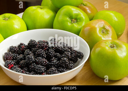 Brombeeren in weiße Schüssel mit Bramley-Äpfel auf Schneidbrett aus Holz Stockfoto