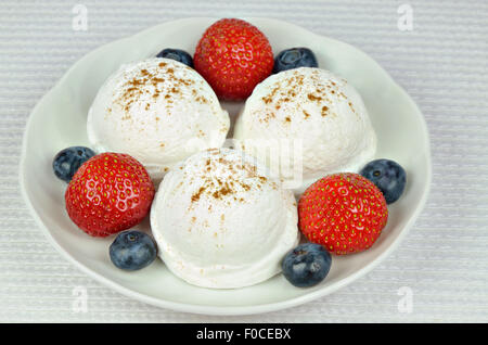 Nahaufnahme von einem weißen Teller mit Vanille-Eis, Erdbeeren und Heidelbeeren, Makro, horizontale Stockfoto