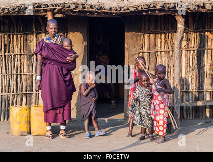 Massai-Familie vor einem traditionellen Haus in ihrer Boma (Dorf) in Tansania, Afrika. Stockfoto