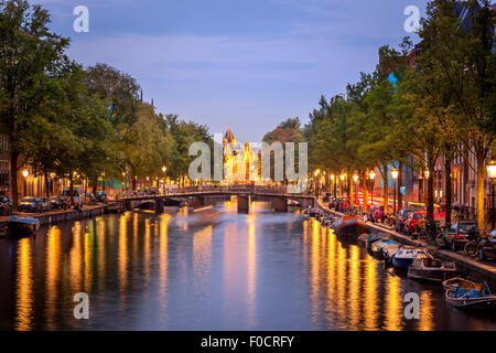 Sehenswürdigkeiten von Amsterdam und die schönen Grachten, bei Einbruch der Dunkelheit beleuchtet. Stockfoto