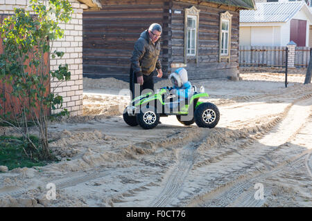 der kleine Junge in warme Overalls geht schnell mit dem Auto Stockfoto