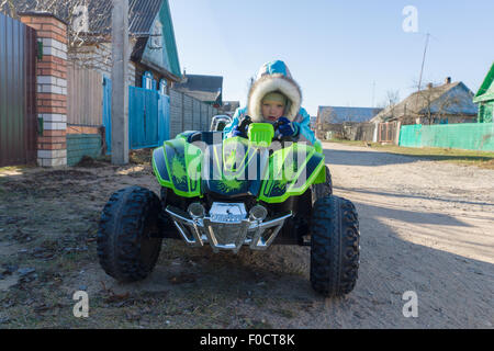 der kleine Junge in warme Overalls geht schnell mit dem Auto Stockfoto