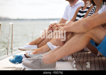 Nahaufnahme von Freunden Beinen sitzen auf dem Deck der yacht Stockfoto