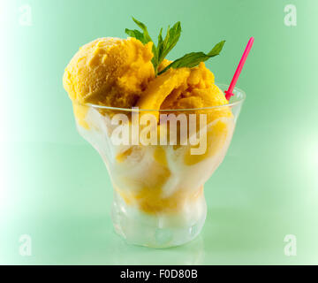 Mango-Sorbet mit Minze in Glasschüssel auf grünem Hintergrund Stockfoto
