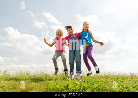 Gruppe von glückliche Kinder springen hoch auf grüner Wiese Stockfoto