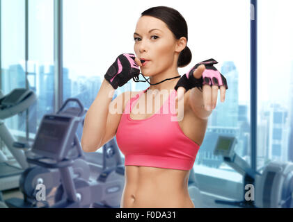 asiatische Frau Trainer weht Pfeife über Fitness-Studio Stockfoto