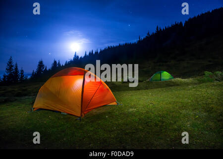 Zwei leuchtend Orange und grün camping Zelte unter Mond, Sterne in der Nacht Stockfoto