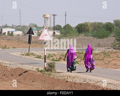 Frauen in der Regel bunten Rajasthani Kleidung zu Fuß entlang einer Landstraße in der Nähe von Pali im westlichen indischen Bundesstaat Stockfoto