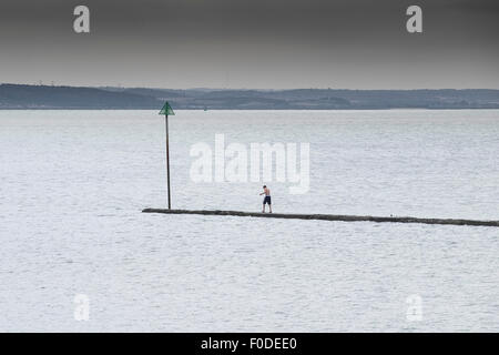 Eine Person, die zu Fuß auf einem wellenbrecher in der Themsemündung. Stockfoto