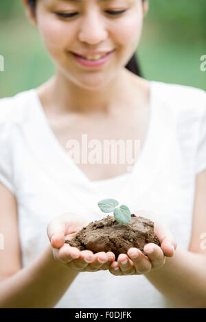 Junge Frau hält einen Sämling Stockfoto