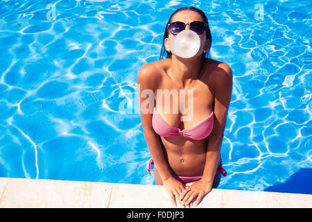 Schöne Frau, die Seifenblase mit Kaugummi im Schwimmen Pool im freien Stockfoto