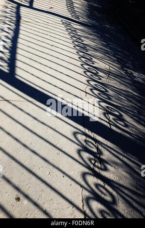 geschmiedeten Zaun Schatten auf einer Asphalt-Strecke Stockfoto