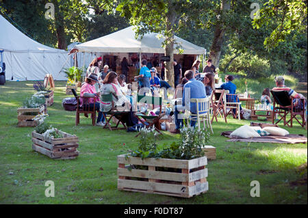 Festivalbesucher zu sitzen, entspannen und trinken im Schatten am Flussufer der Mündung am Hafen Eliot Festival Cornwall Stockfoto