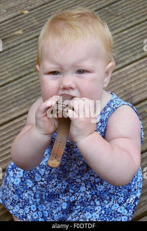 Ein Zahnen zehn Monate altes Baby sitzen und beißen auf ein Armband zur Linderung von Schmerzen und Beschwerden der Zahn weh. Stockfoto