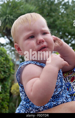 Ein Zahnen 10 Monate alten baby schreit vor Schmerzen und Beschwerden während gehalten und getröstet. Stockfoto