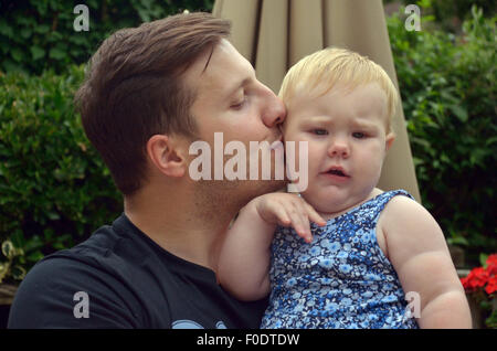 Ein junger Vater liebevoll küssen seine zehn Monate alte Tochter. Stockfoto