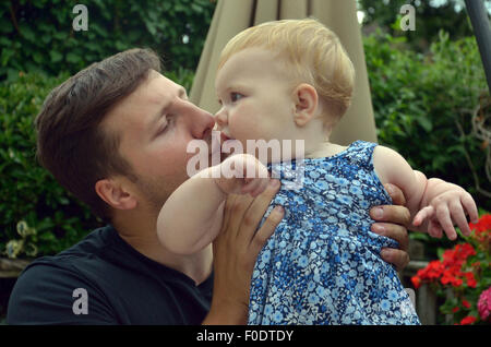 Ein junger Vater liebevoll küssen seine zehn Monate alte Tochter. Stockfoto