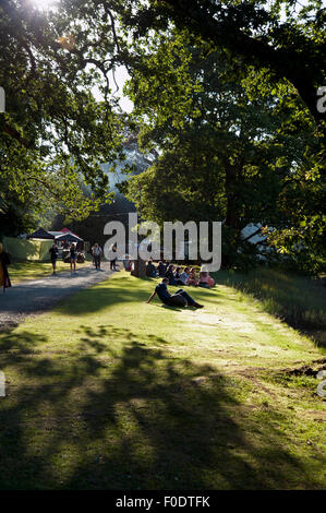 Festivalbesucher zu sitzen, entspannen und trinken im Schatten am Flussufer der Mündung am Hafen Eliot Festival Cornwall Stockfoto