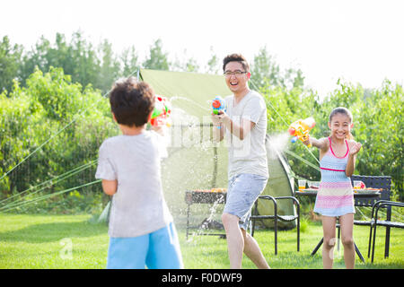 Glücklicher Vater und die Kinder spielen Spritzpistolen Stockfoto